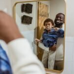 Black father and son brushing teeth in bathroom