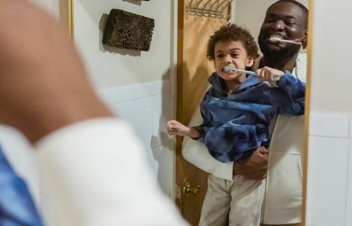 Black father and son brushing teeth in bathroom