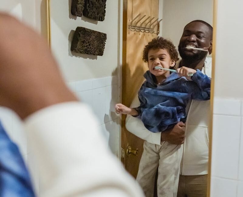 Black father and son brushing teeth in bathroom