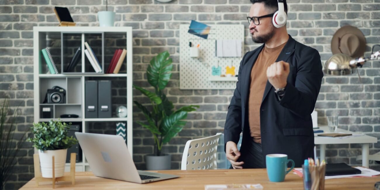 a man wearing headphones standing in front of a laptop