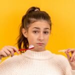 woman in white knit sweater holding red pen