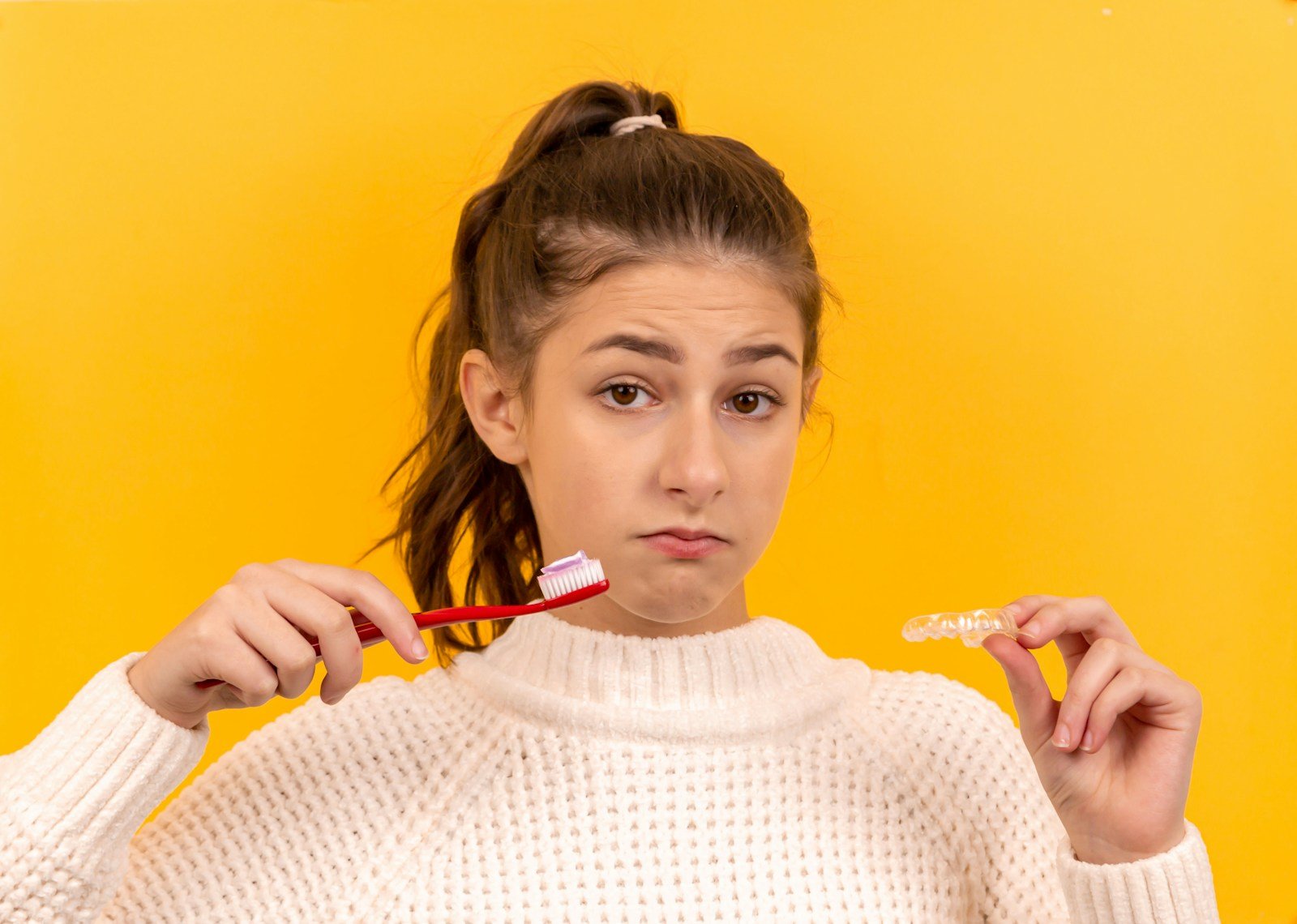 woman in white knit sweater holding red pen