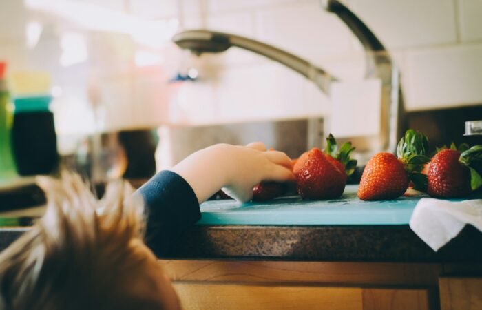 child picking strawberries in kitchen
