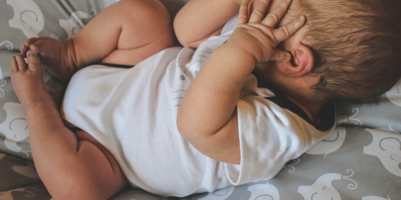 baby in white shirt lying on bed