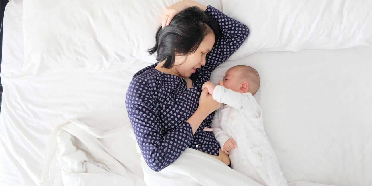 woman and baby lying on bed