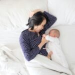 woman and baby lying on bed