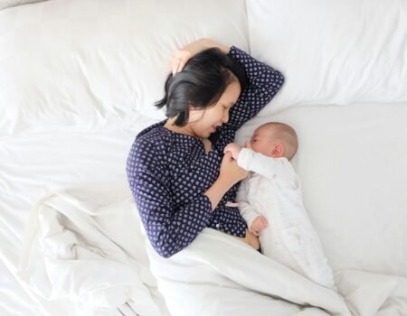 woman and baby lying on bed